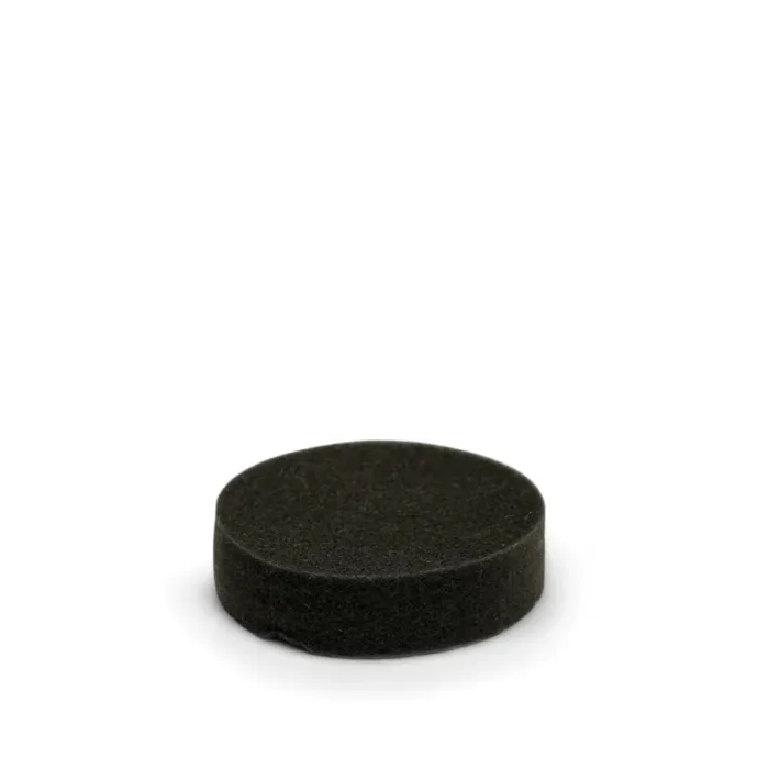 A black, cylindrical, and solid hockey puck rests on a plain white background, slightly casting a soft shadow beneath it.